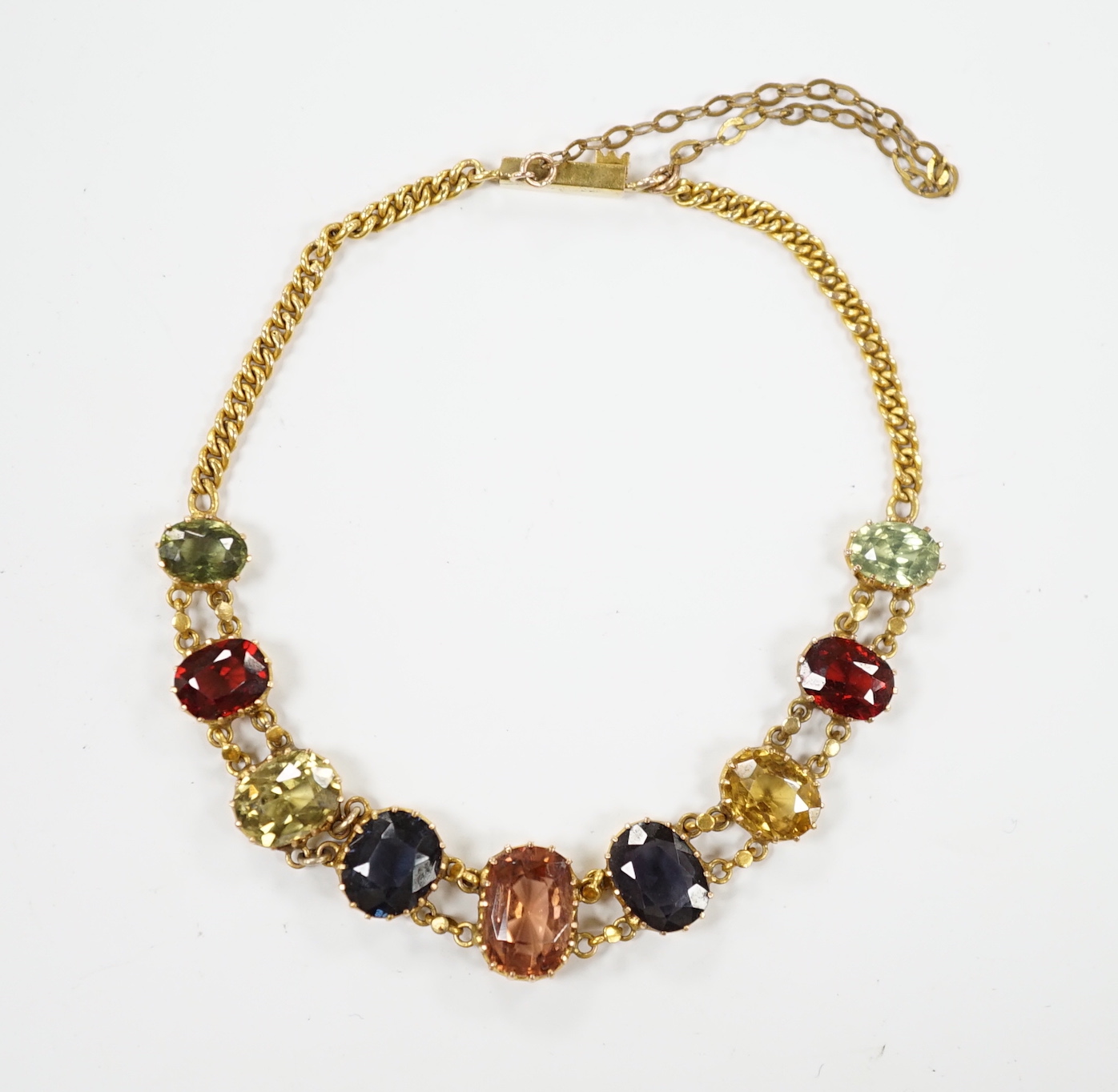 An early 20th century yellow metal and graduated multi-coloured oval cut zircon? set bracelet, 15.5cm, gross weight 7 grams.